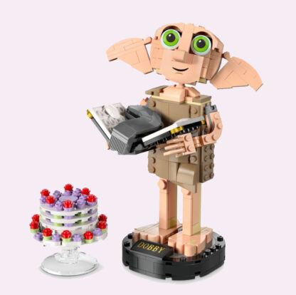 Lego dobby standing holding a Lego version of Tom Riddle's diary with a Lego cake on the ground beneath